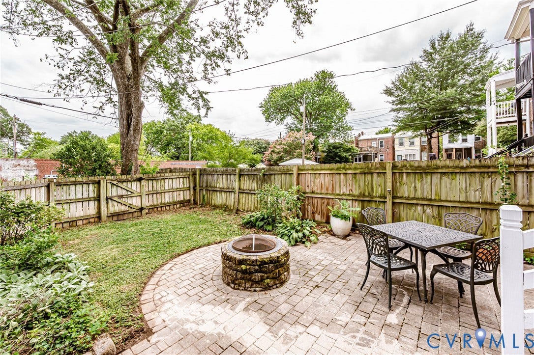 Private backyard featuring a paver patio with a stone fire pit