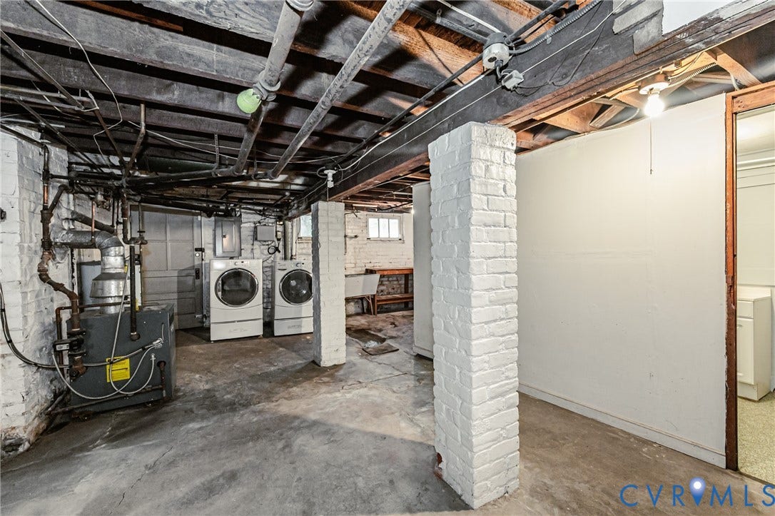 Unfinished basement featuring a concrete floor, exposed ceiling joists, and painted brick support columns