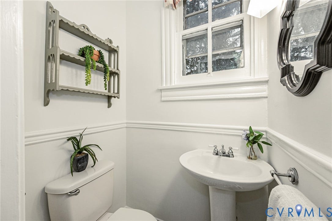Well-appointed powder room featuring a pedestal sink with chrome fixtures, a window with exterior visibility, decorative wall molding, and a wall-mounted mirror