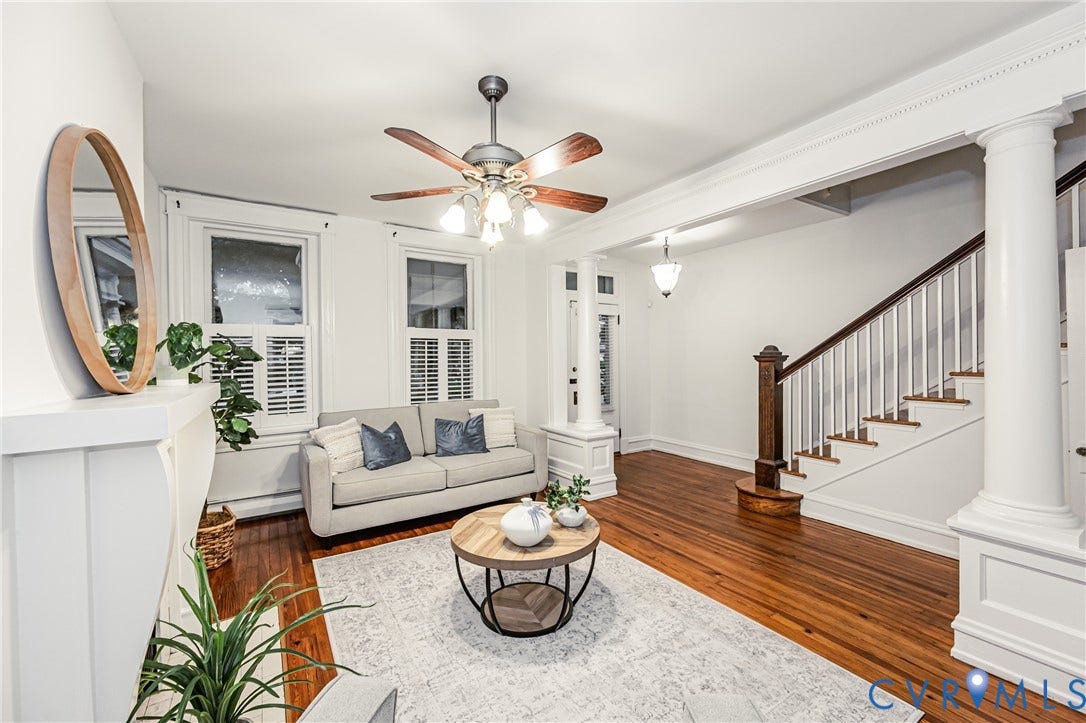Living area featuring hardwood flooring, a decorative fireplace with a mantel, and architectural columns