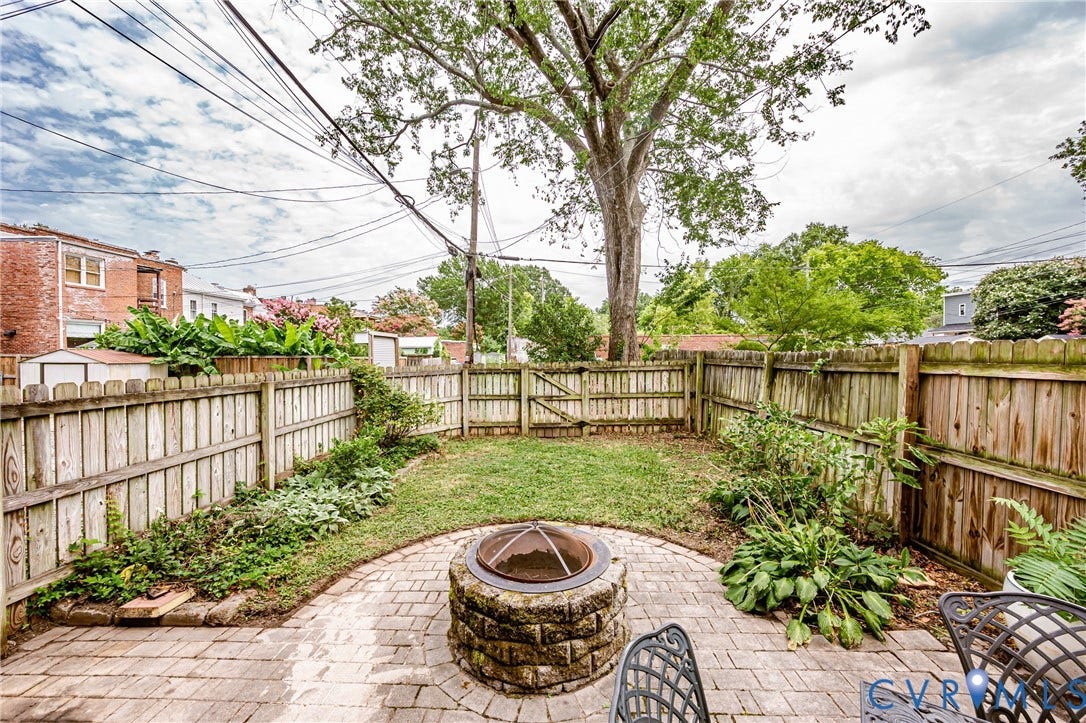 Patio featuring a fire pit with a stone base, a brick paver surface, and a surrounding privacy fence
