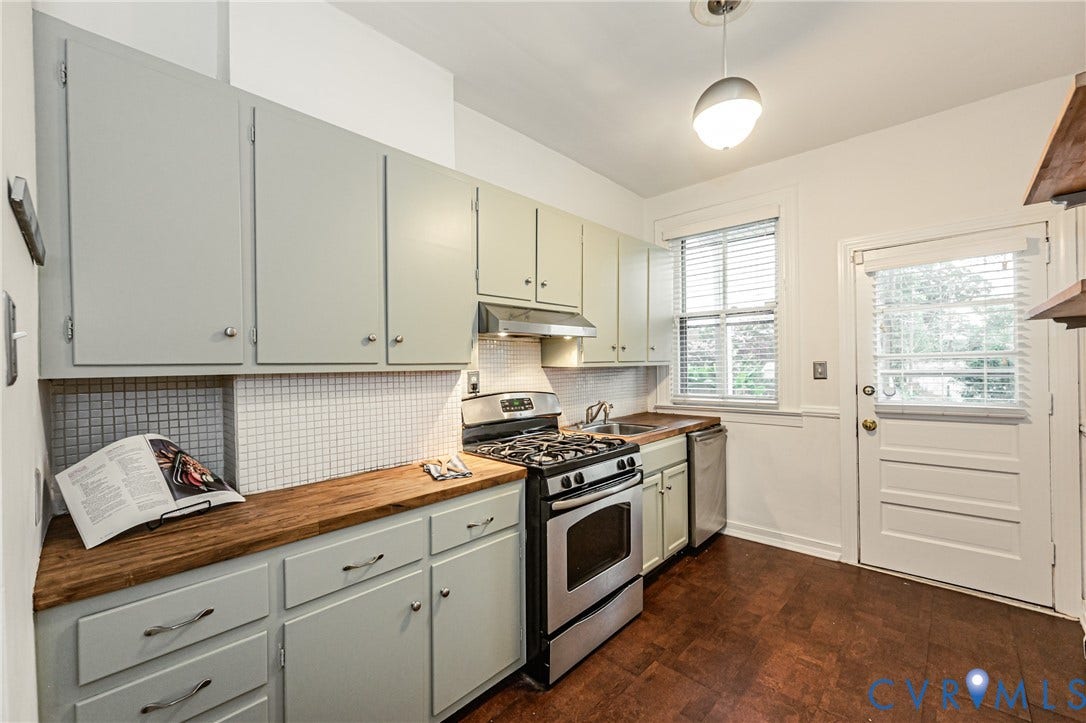 Kitchen featuring light-toned cabinetry, wood-finish countertops, and a white square tile backsplash
