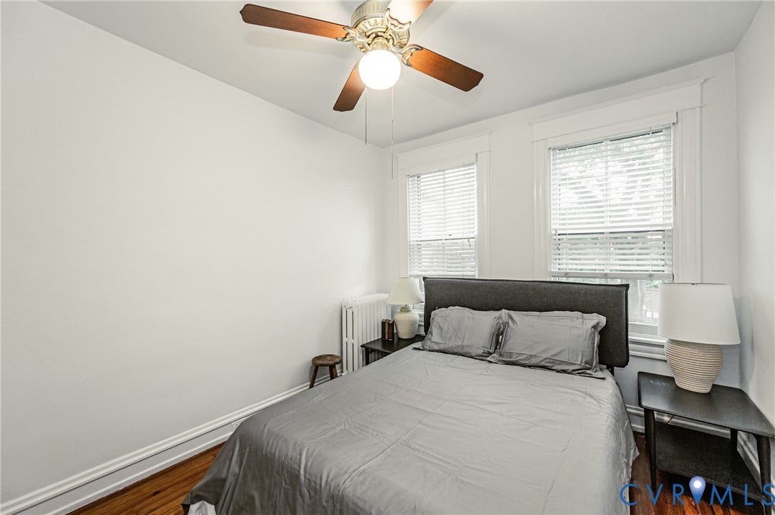 Room featuring two windows with white blinds, a ceiling fan with light fixture, white baseboards, and wood flooring