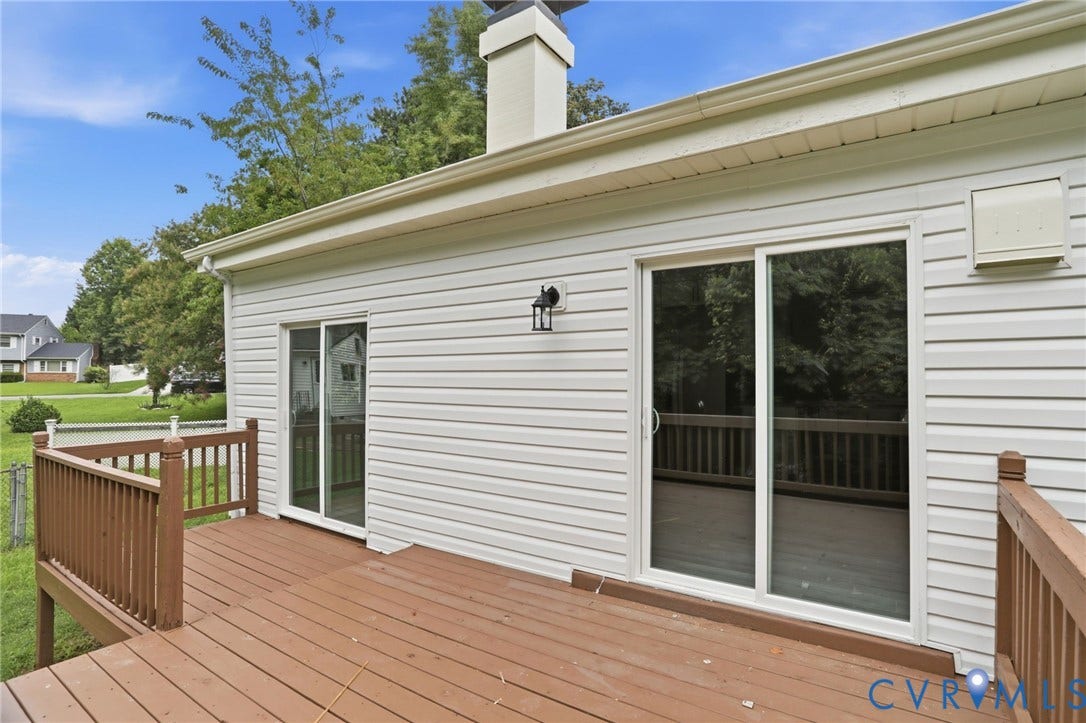 5301 Dalglish Road, Henrico, VA 23223 Expansive wood-finish deck with brown railing, featuring two white-framed sliding glass doors