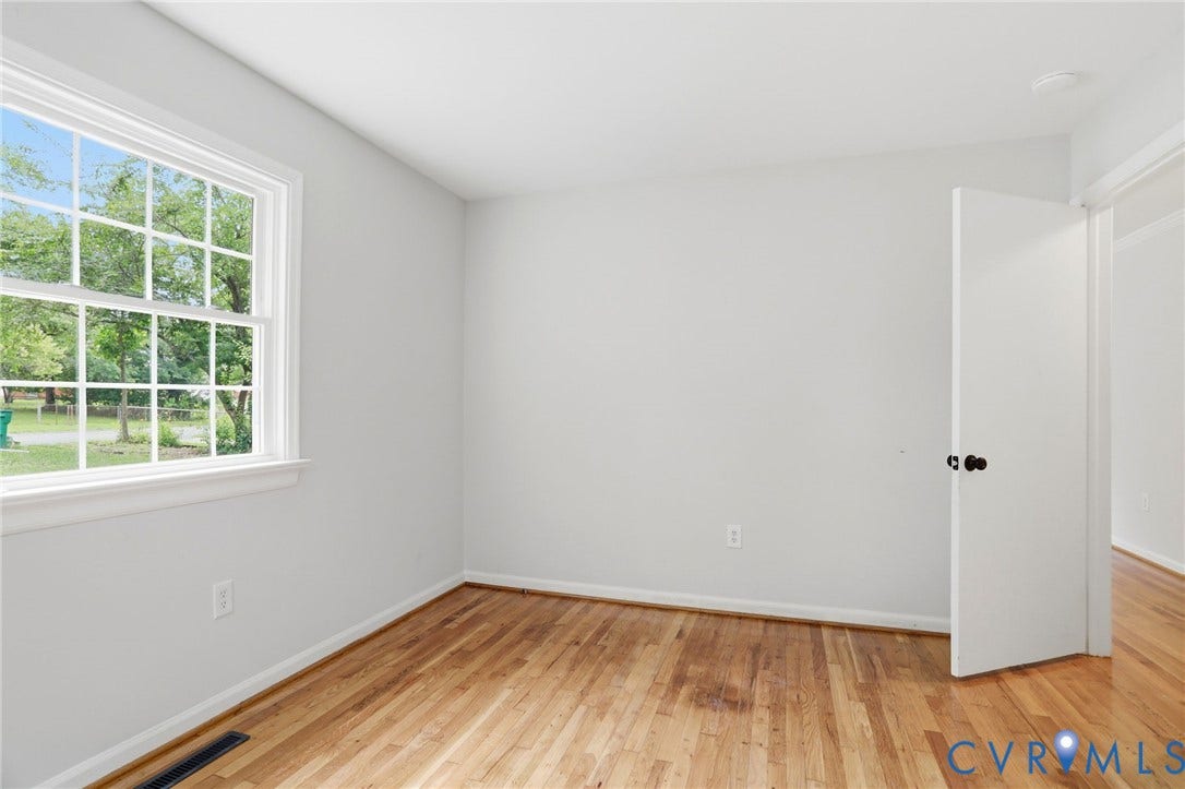 5301 Dalglish Road, Henrico, VA 23223 Light-filled room featuring wood-finish flooring, white trim, a large window with multiple panes, and a white interior door with dark hardware