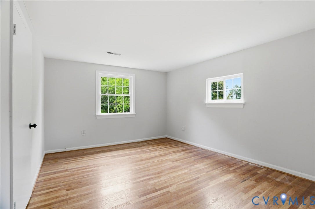 5301 Dalglish Road, Henrico, VA 23223 Light-filled room featuring wood-finish flooring, two windows with white trim, and a neutral wall color