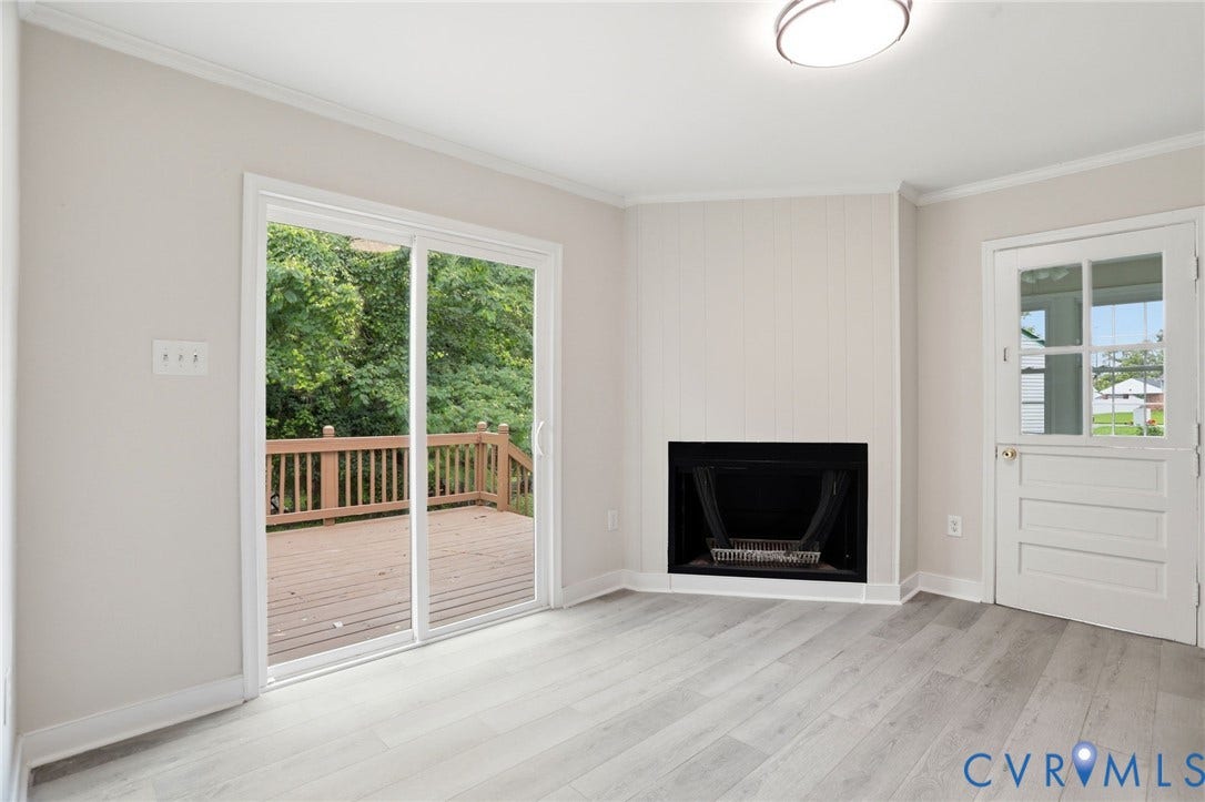 5301 Dalglish Road, Henrico, VA 23223 Living area featuring light wood-finish flooring, a built-in fireplace, and a sliding glass door opening to a wooden deck