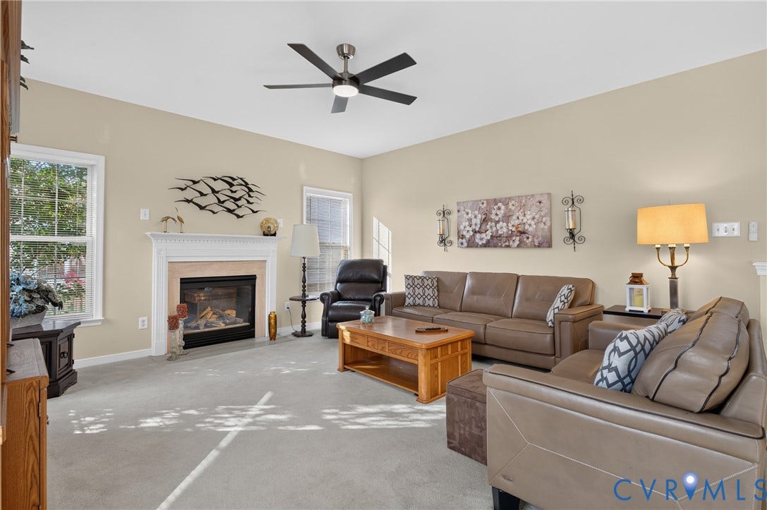10817 Correnty Drive, Glen Allen, VA 23059 Carpeted living space featuring a fireplace with a white mantel, ceiling fan, and multiple windows