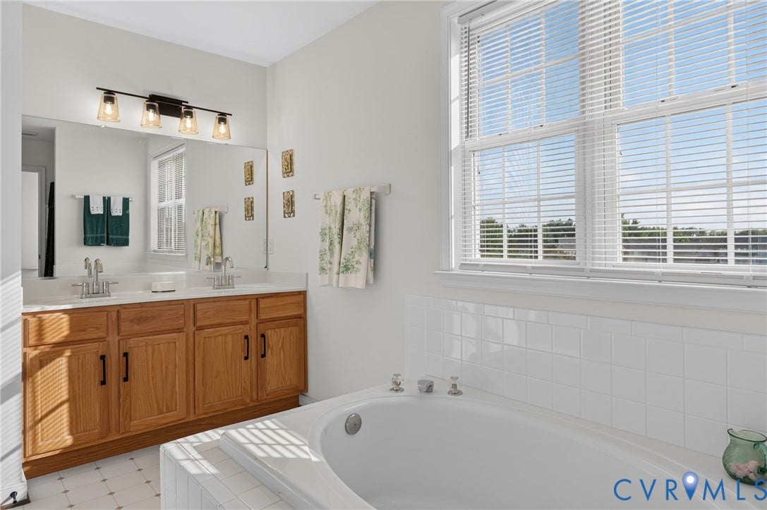 10817 Correnty Drive, Glen Allen, VA 23059 Bathroom with a dual vanity featuring wood-finish cabinetry, a light-toned countertop, and dual sinks