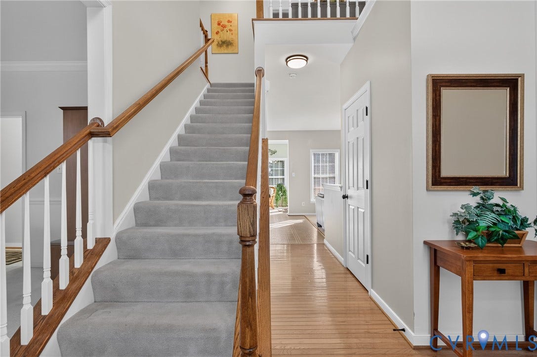 10817 Correnty Drive, Glen Allen, VA 23059 Inviting entryway featuring a carpeted staircase with wood handrails, hardwood flooring, and a paneled interior door
