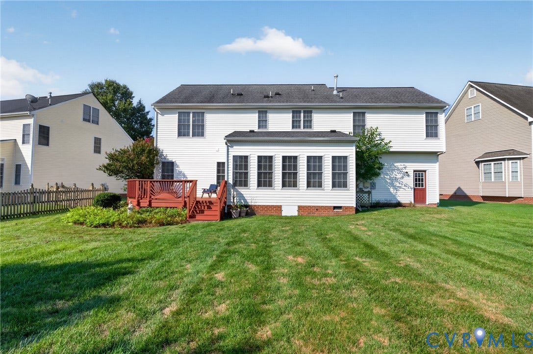 10817 Correnty Drive, Glen Allen, VA 23059 Expansive backyard featuring a manicured lawn, a multi-level wood deck, a sunroom with multiple windows, white siding exterior, and a red rear entry door