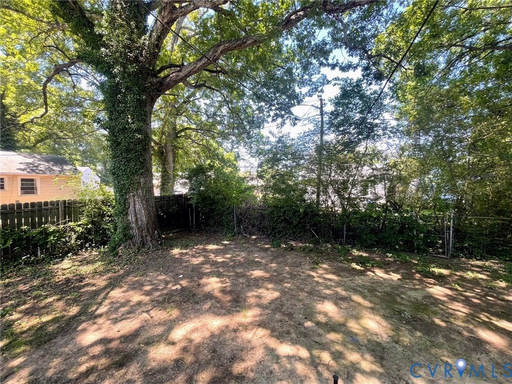 1417 Bowen Street, Oak Grove, Richmond, VA 23224 Spacious backyard featuring a prominent mature tree with climbing ivy, partial fencing, and a wooded view