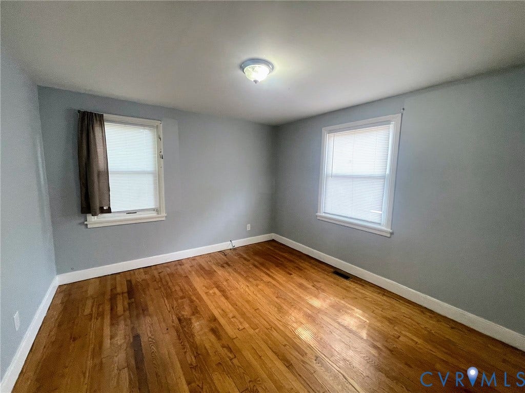 1417 Bowen Street, Oak Grove, Richmond, VA 23224 Hardwood flooring throughout featuring white baseboard trim, two windows with blinds, and neutral wall paint