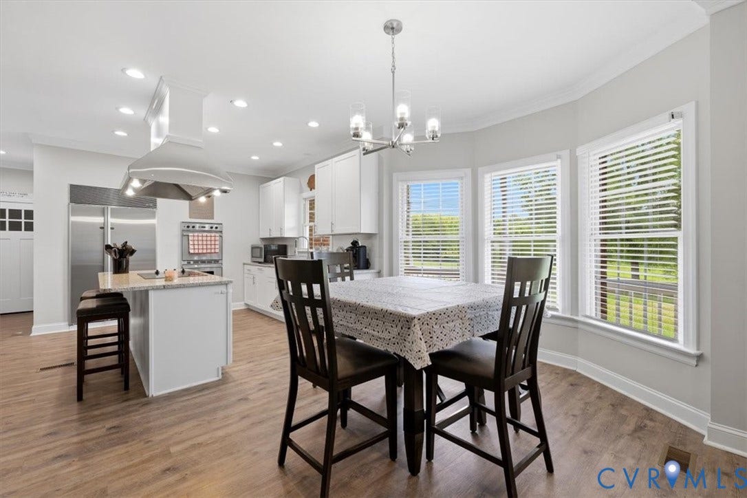 Kitchen featuring wood-finish flooring, white cabinetry, and stainless steel appliances
