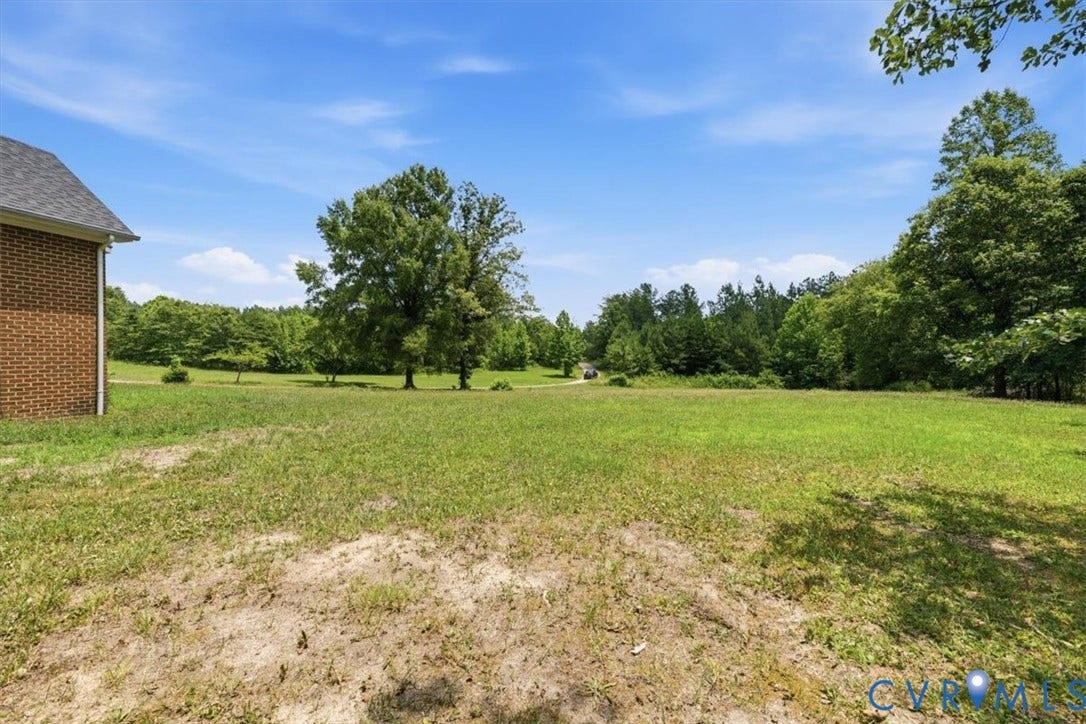 Expansive outdoor space featuring a large grassy area, mature trees, and a brick-sided structure