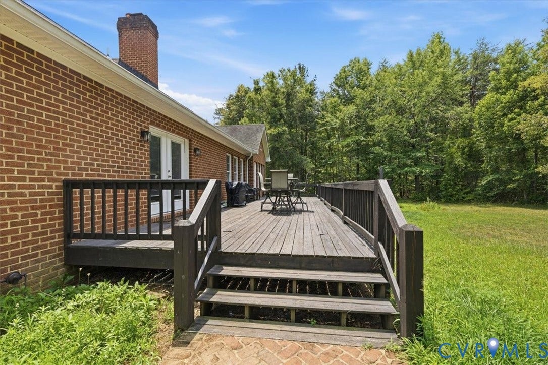 Wood deck with stairs, brick exterior, and white double doors