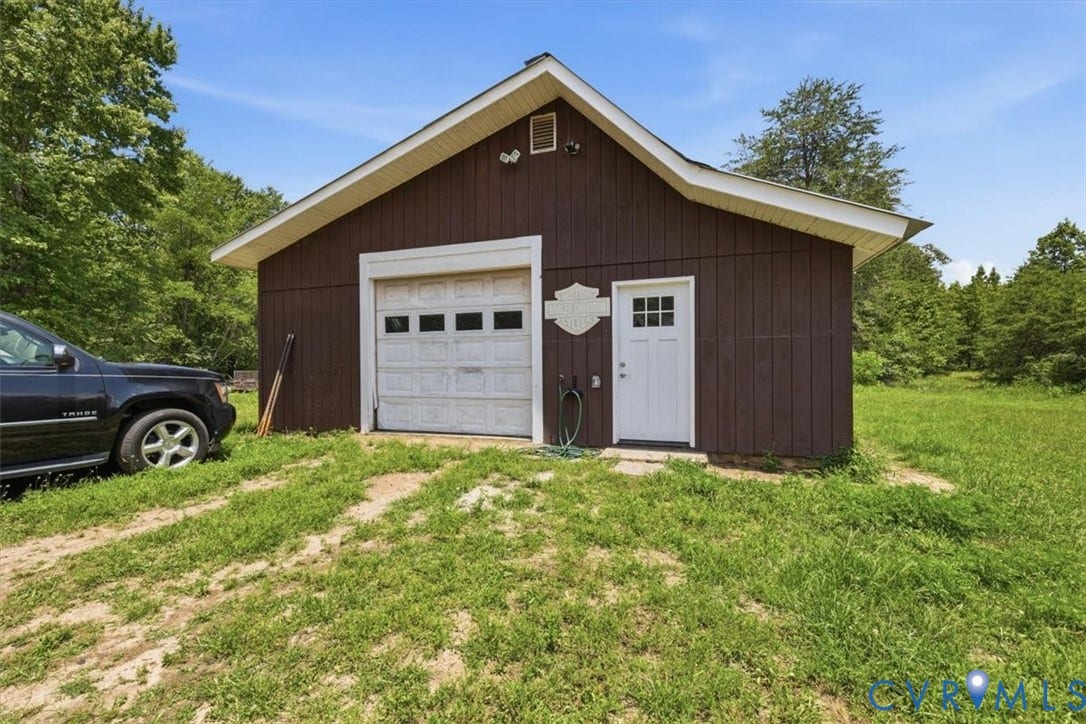 Detached outbuilding featuring brown vertical siding, a white garage door, and a white side entry door with a multi-pane window