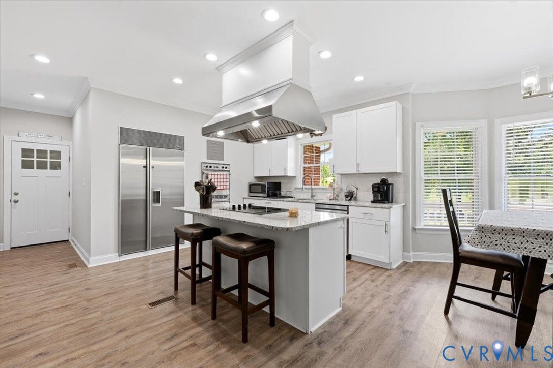 Modern kitchen featuring an island with a stainless steel range hood, recessed lighting, wood-finish flooring, white cabinetry, and stainless steel appliances