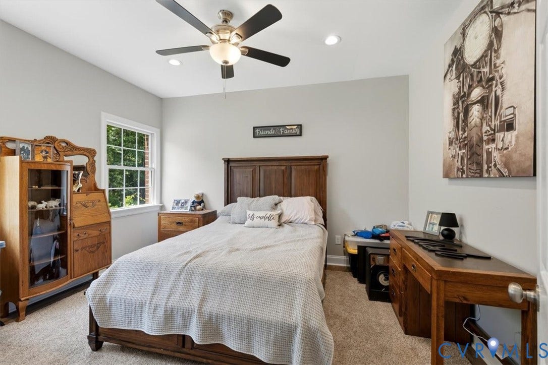 Bedroom featuring light gray walls, plush carpeting, a multi-pane window, and a ceiling fan with integrated lighting