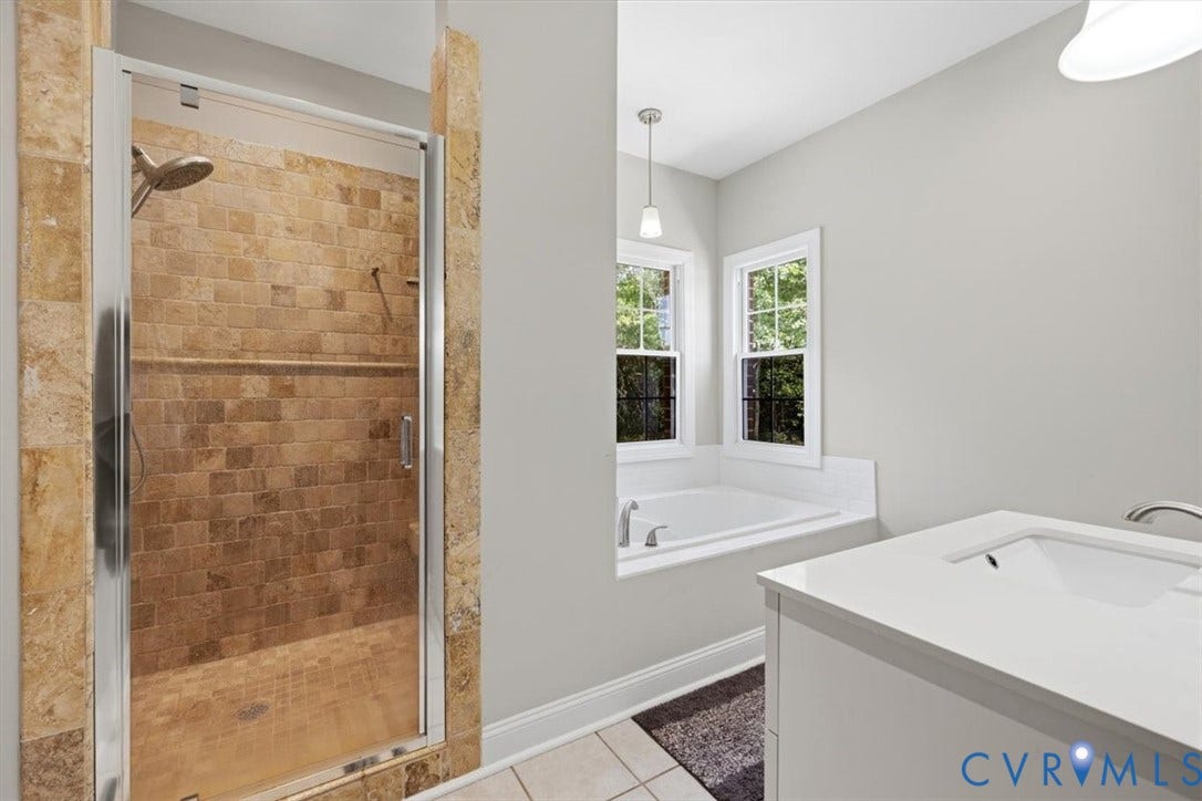 Tiled shower with glass enclosure, featuring a built-in shelf and rainfall showerhead