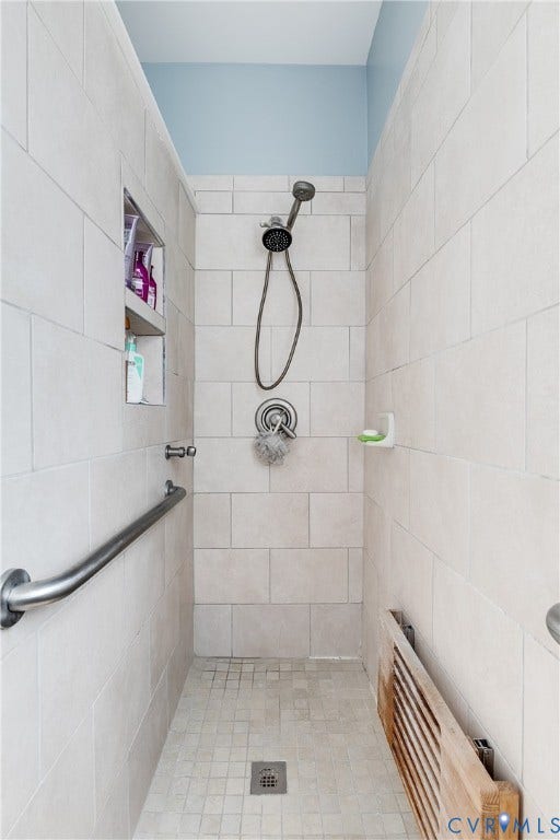 Primary En-Suite Tiled Shower Featuring Roll-In Wheelchair Accessibility and Grab Bars.