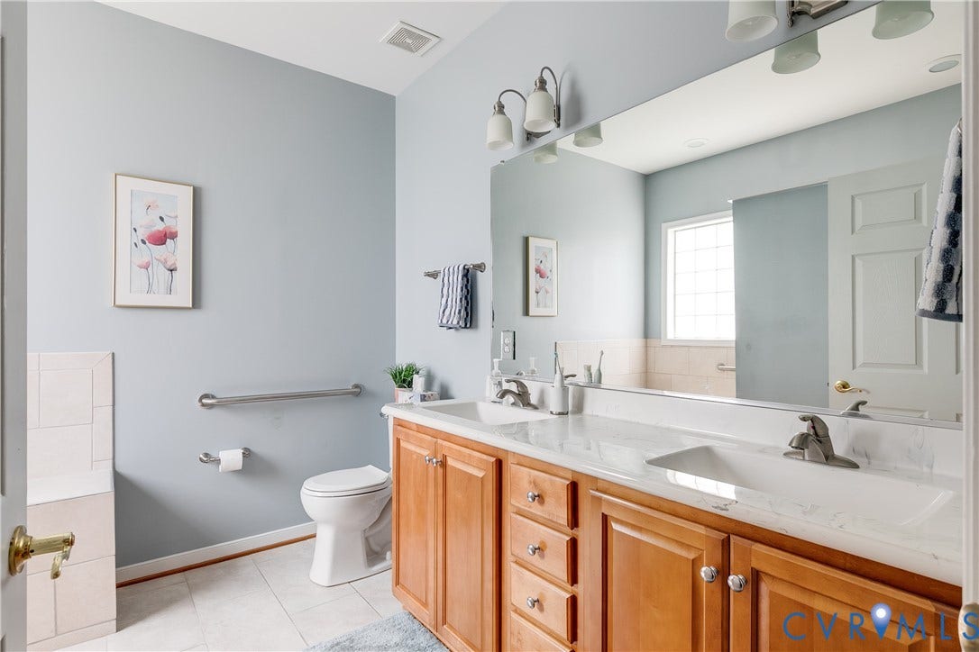 Primary En-Suite Bath Featuring Tile Flooring and Double Vanity.