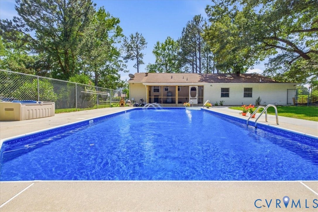 In-ground swimming pool with an integrated water feature and surrounding concrete decking