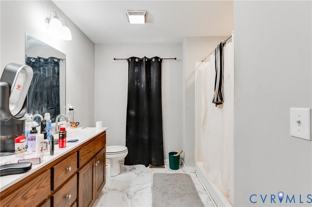 24580 St James Road, Amelia, VA 23083 Bathroom featuring a wood-finish vanity with an integrated countertop and sink, a wall-mounted mirror, overhead lighting, and a shower with a white curtain
