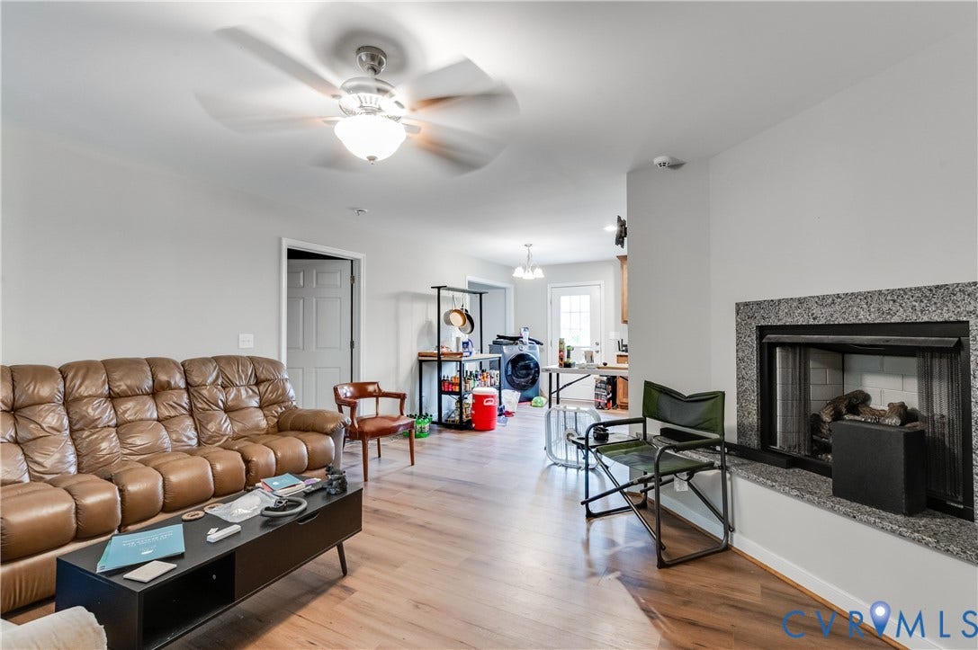 24580 St James Road, Amelia, VA 23083 Living room featuring wood-finish flooring, a ceiling fan with integrated lighting, a fireplace with a granite surround, and a clear doorway