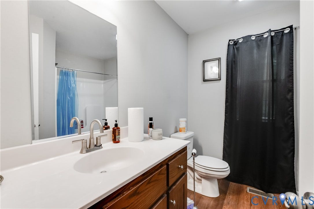24580 St James Road, Amelia, VA 23083 Bathroom featuring a wood-finish vanity with a white countertop and integrated sink, brushed nickel faucet, and wood-finish flooring