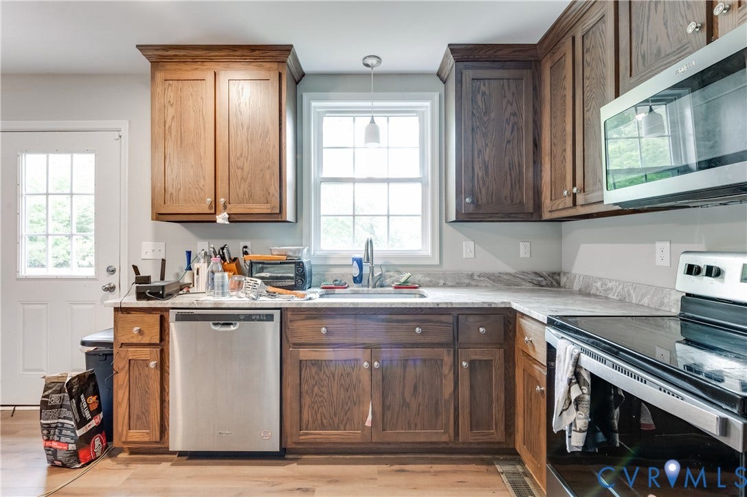 24580 St James Road, Amelia, VA 23083 Kitchen featuring wood-finish cabinetry, light-toned countertops, stainless steel appliances, a window above the sink, and wood-finish flooring