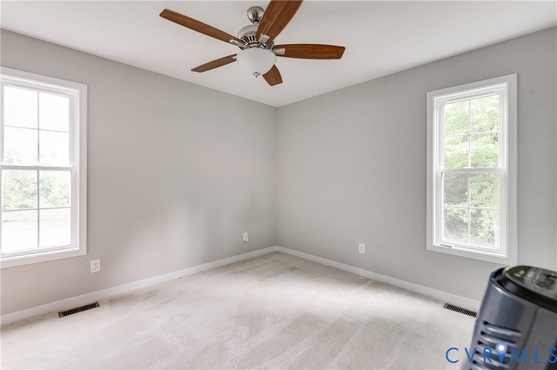 24580 St James Road, Amelia, VA 23083 Carpeted room with light grey walls, two windows, and a ceiling fan with light fixture