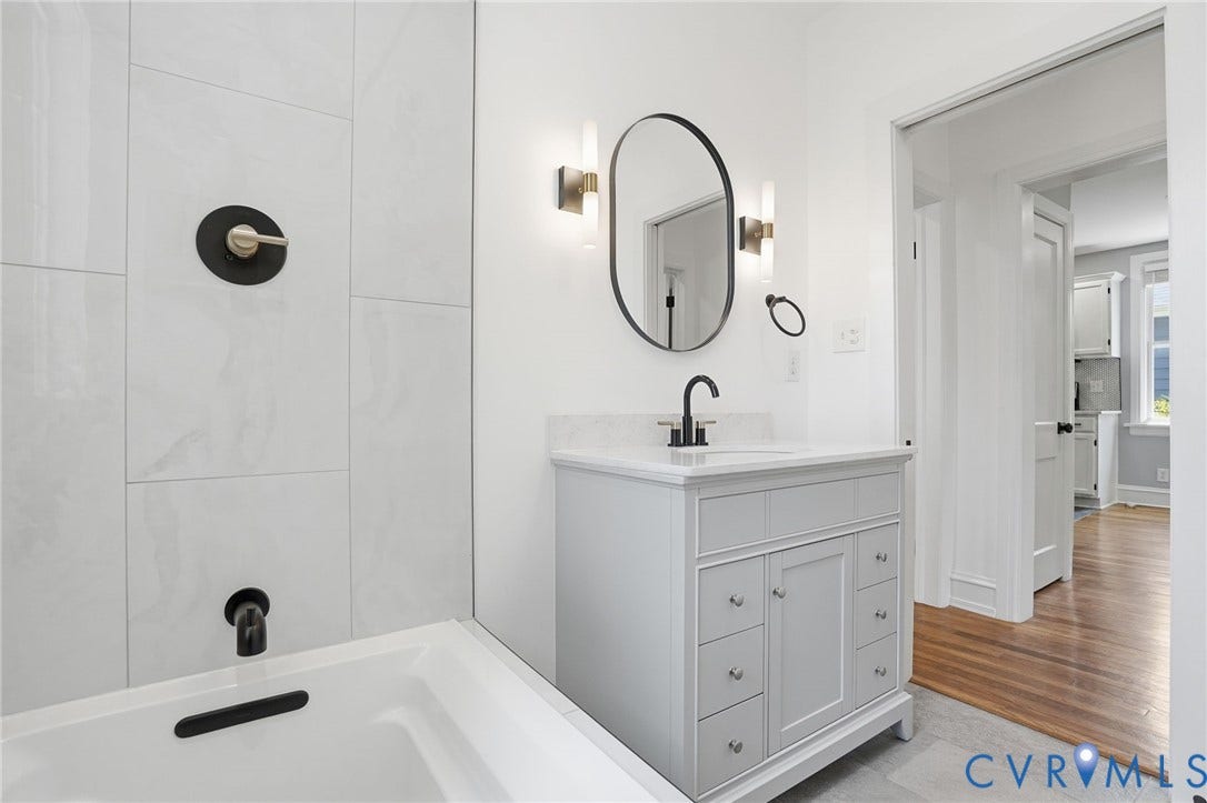6929 Woodrow Terrace, Richmond, VA 23228 Bathroom featuring a white vanity with integrated sink and quartz countertop, oval-framed mirror, and modern wall sconces