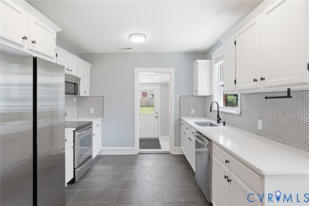 6929 Woodrow Terrace, Richmond, VA 23228 White cabinetry with matte black hardware, stainless steel appliances, solid surface countertops, penny tile backsplash, and dark tile flooring
