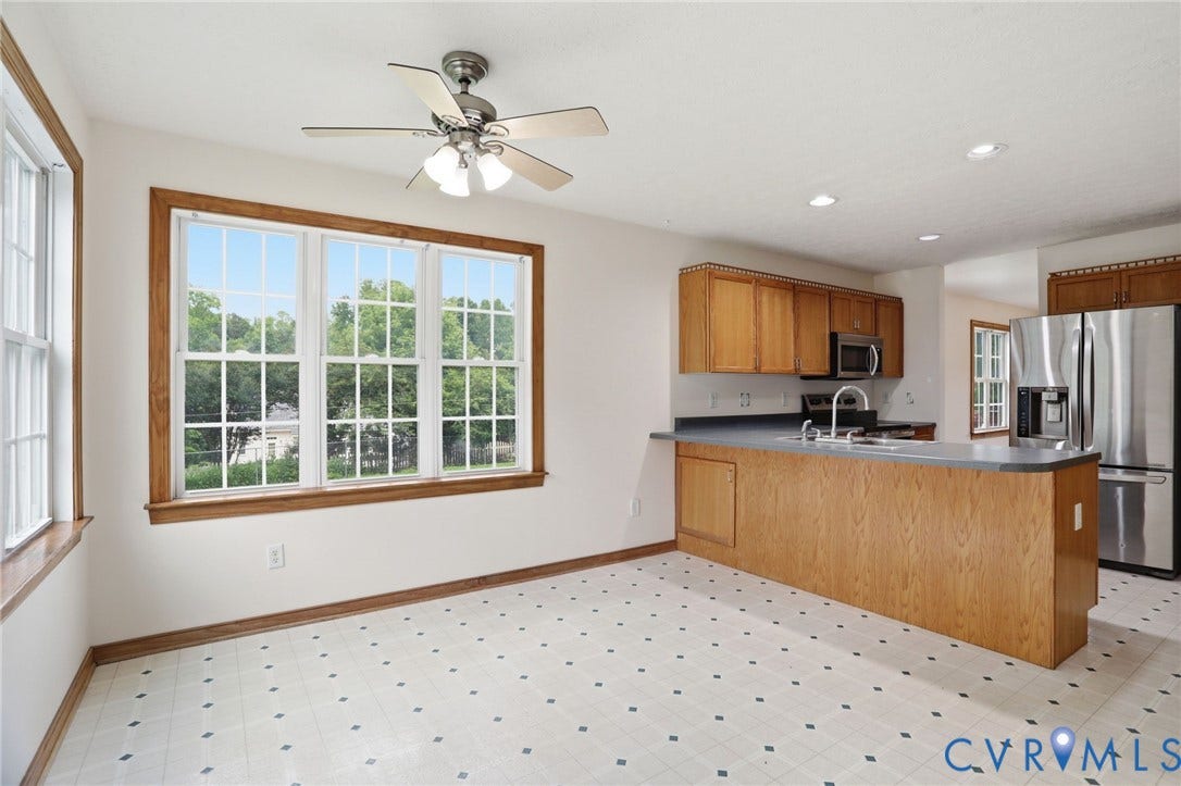 Eat-in kitchen featuring a multi-pane window, oak cabinetry, stainless steel appliances, and a ceiling fan with light