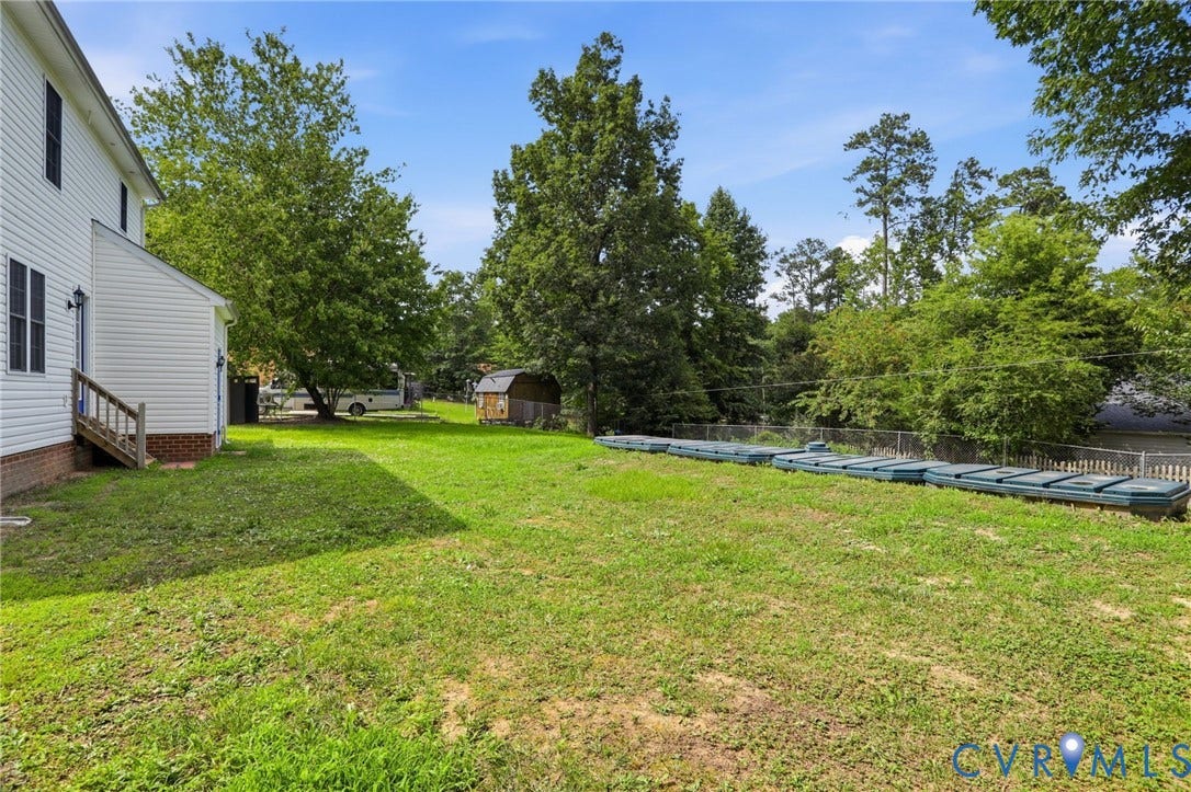 Expansive green lawn with a white vinyl-sided exterior and a small wooden shed