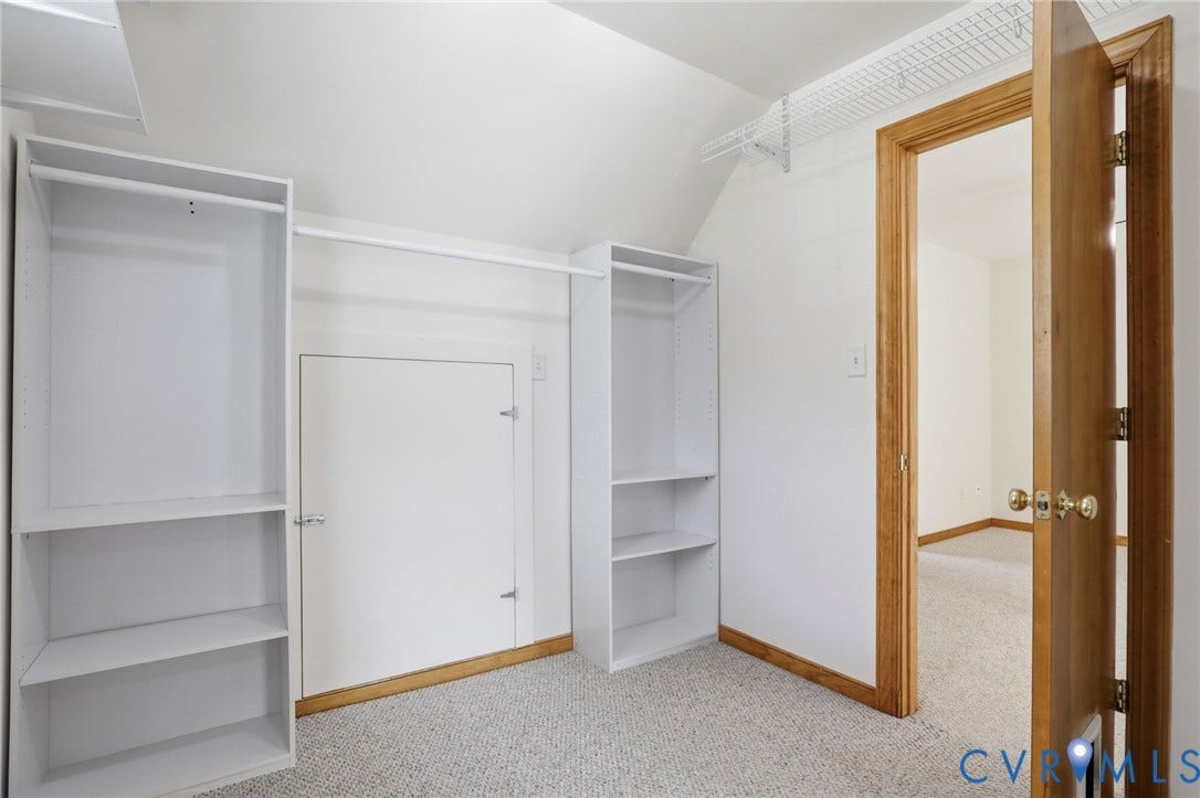 Storage area featuring built-in shelving, hanging rods, wire shelving, and light-toned carpeting
