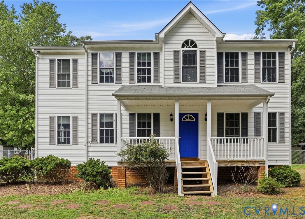 Two-story residence featuring white vinyl siding, a covered front porch with white railing, and a vibrant blue entry door