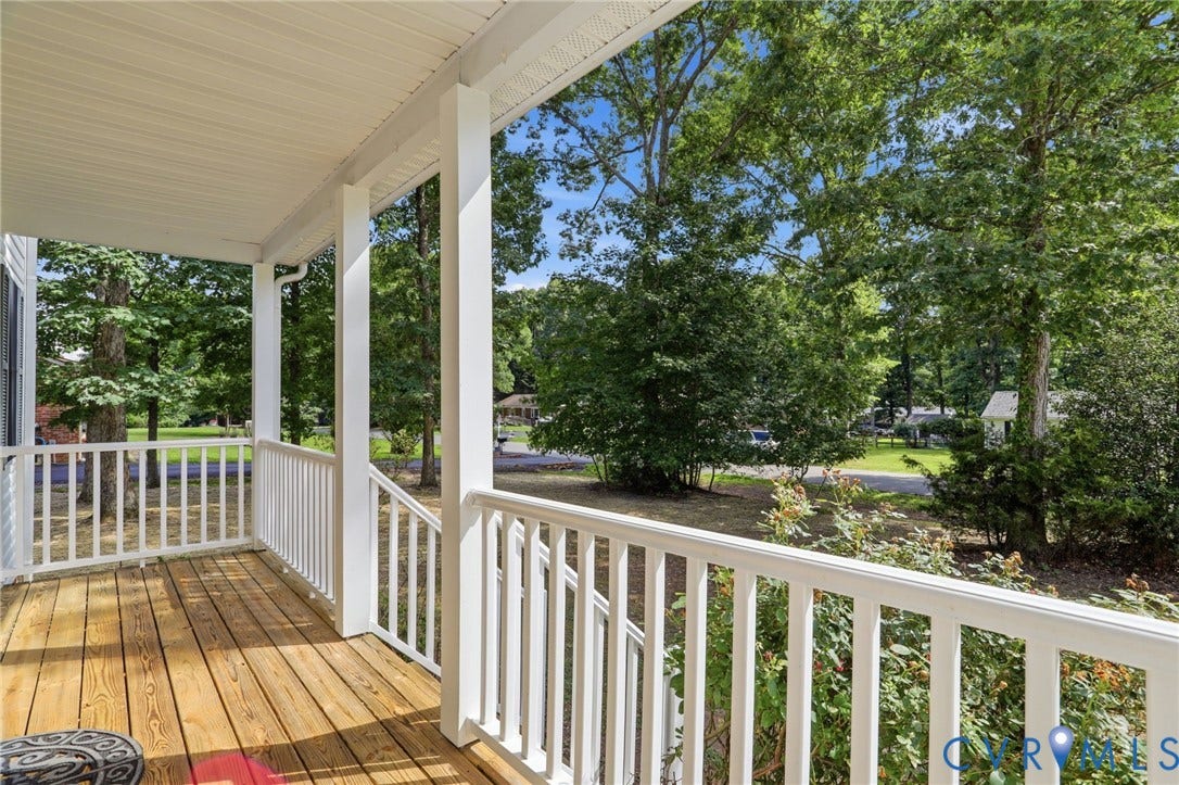 Covered front porch featuring wood-finish flooring, white railing, and white support columns
