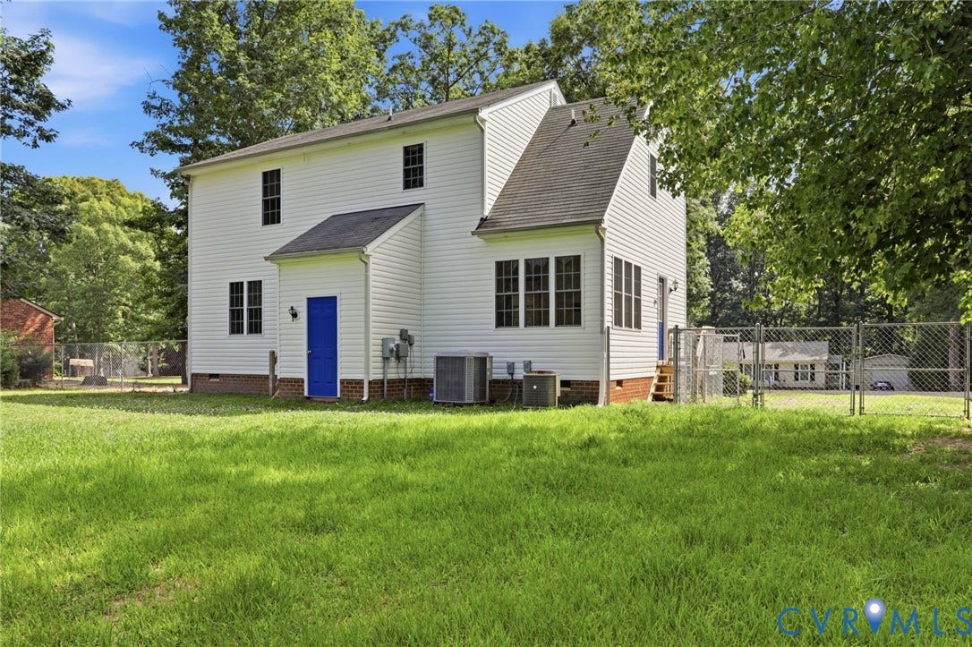 Expansive grassy yard surrounding a white siding residence with a vibrant blue rear entry door