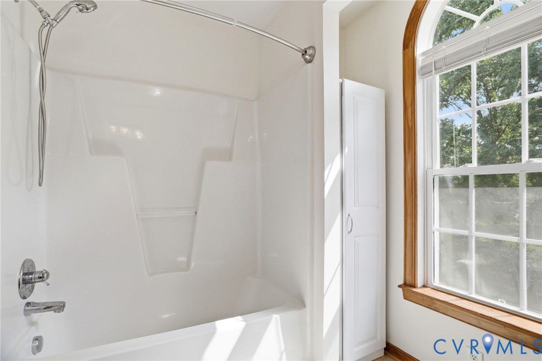 White fiberglass tub and shower combination with chrome fixtures