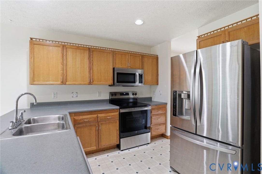 Kitchen featuring wood cabinetry, stainless steel appliances, a double basin sink, and laminate countertops