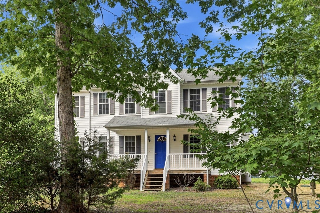 Two-story residence featuring white siding, a covered front porch with white railings, and a vibrant blue entry door