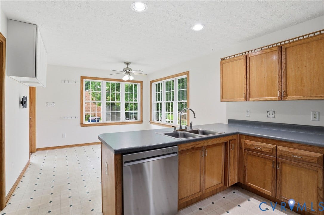 Kitchen featuring wood cabinetry, stainless steel dishwasher, dual basin sink, and a multi-pane bay window