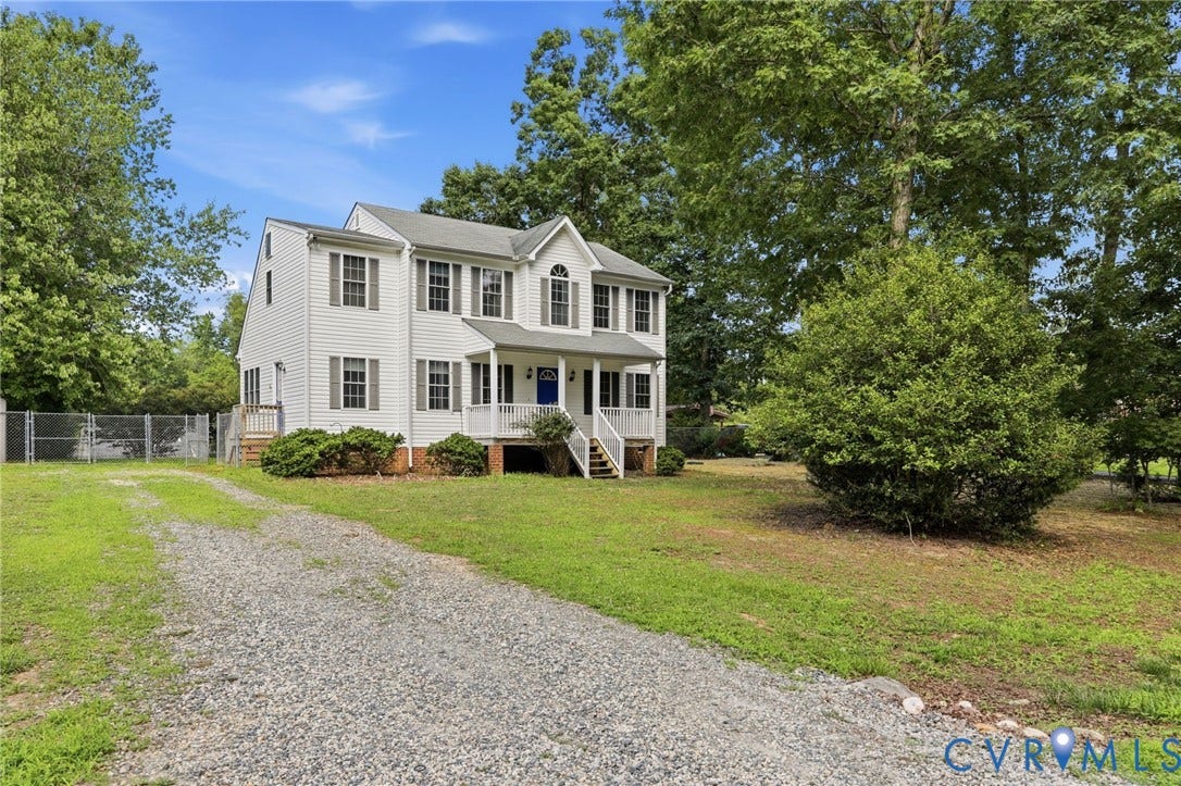 Two-story residence featuring white siding, a covered front porch, and a gravel driveway