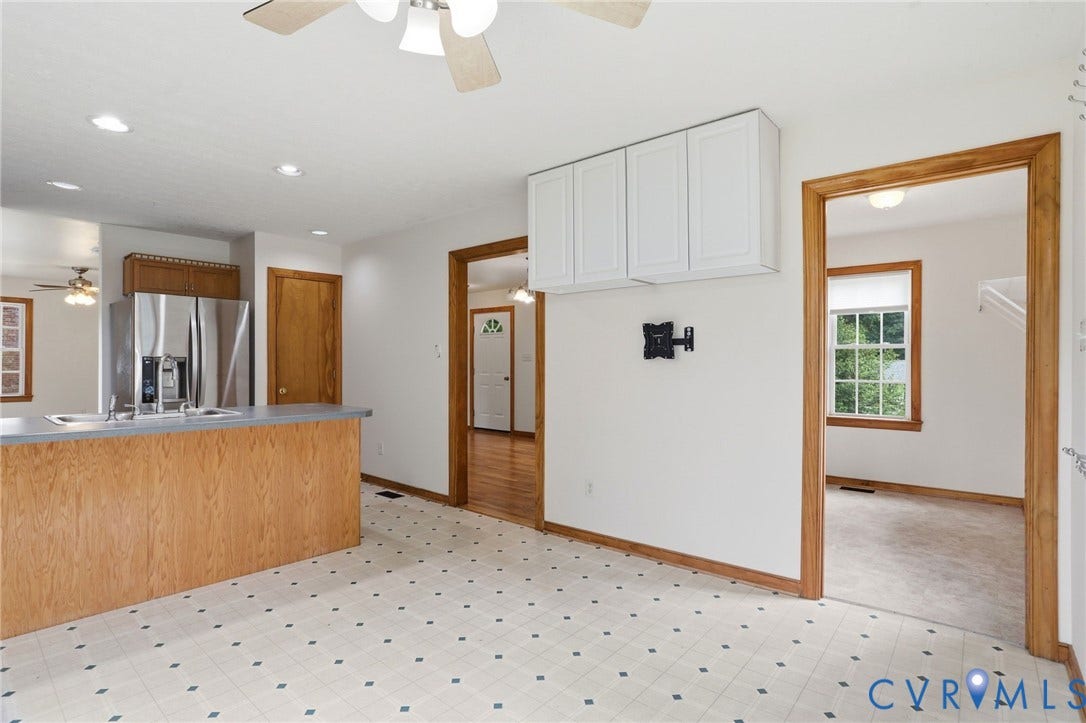 Kitchen and living area featuring a breakfast bar with wood-finish paneling, stainless steel refrigerator, recessed ceiling lighting, and a neutral wall color