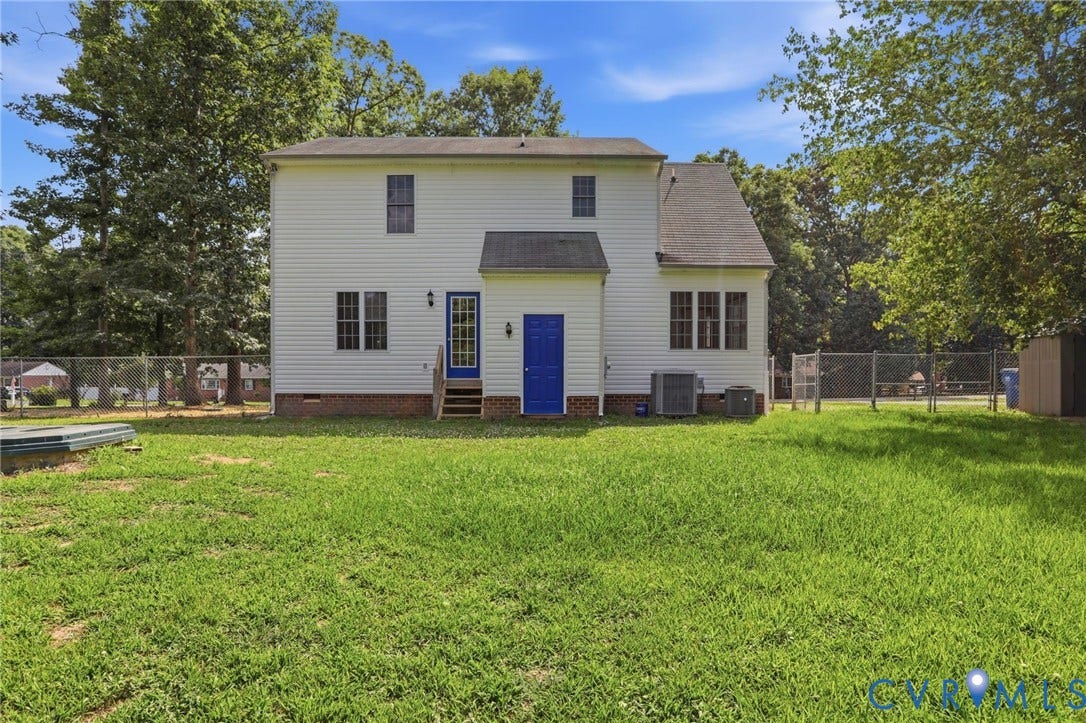 Expansive rear yard featuring a two-story residence with white siding, multiple windows, a rear deck with steps, and two vibrant blue doors