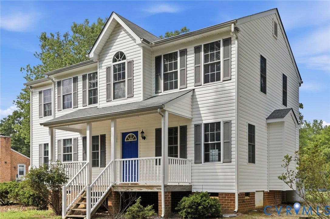 White two-story home with a blue front door, gray shutters, and a covered porch