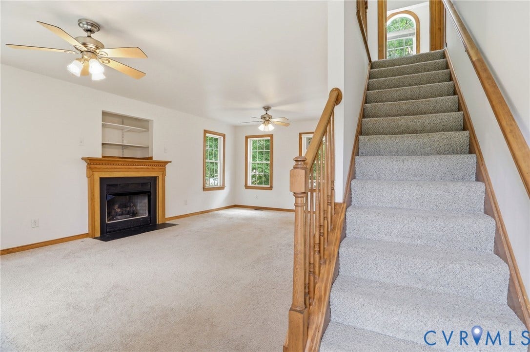 Carpeted staircase with wooden banister, featuring an arched window above