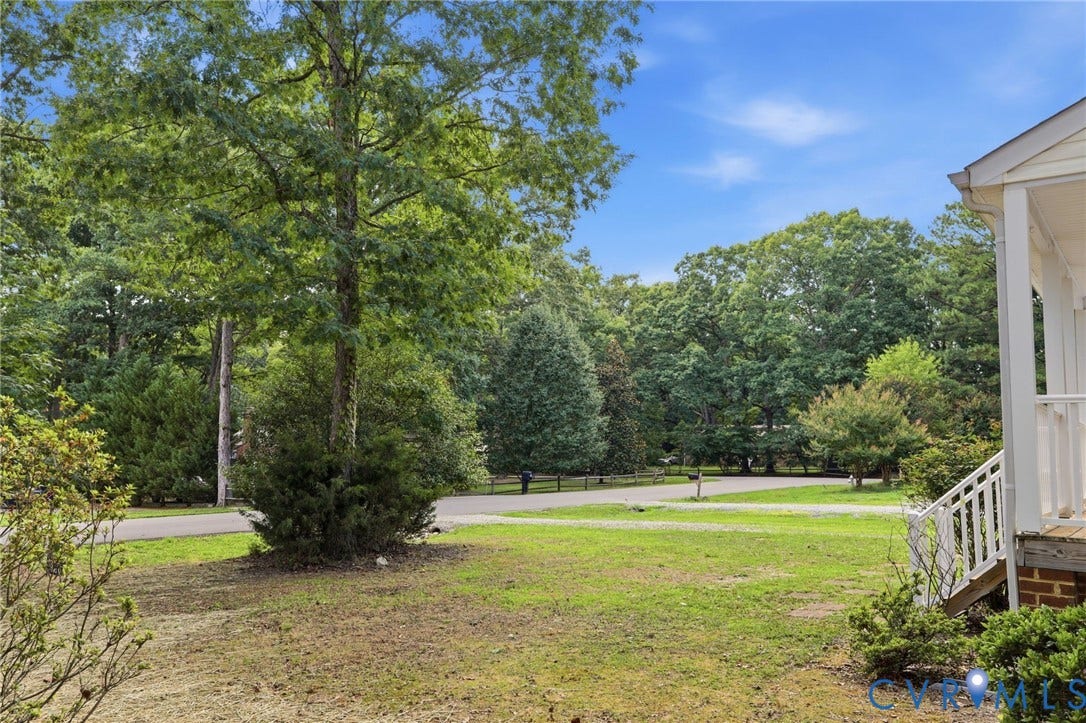 Expansive front yard featuring mature trees and established greenery